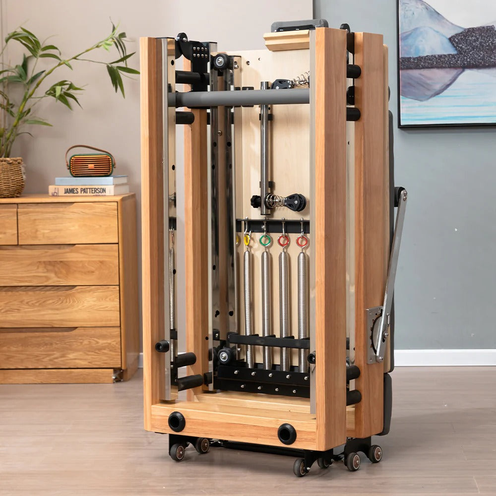 Foldable Oak Pilates Reformer folded beside a sideboard